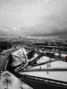 A black and white photo of İstanbul's cityscape covered in snow, capturing its urban roads and skyline.