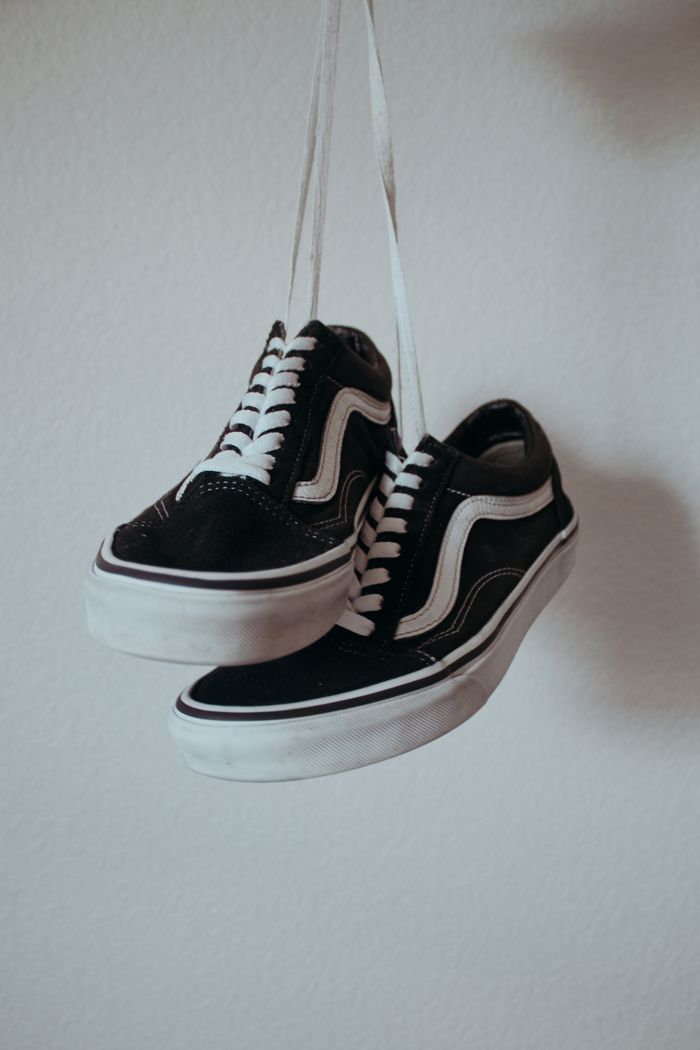 Black sneakers with white shoelaces hanging on a wall. — photo by adanvdo on Pexels
