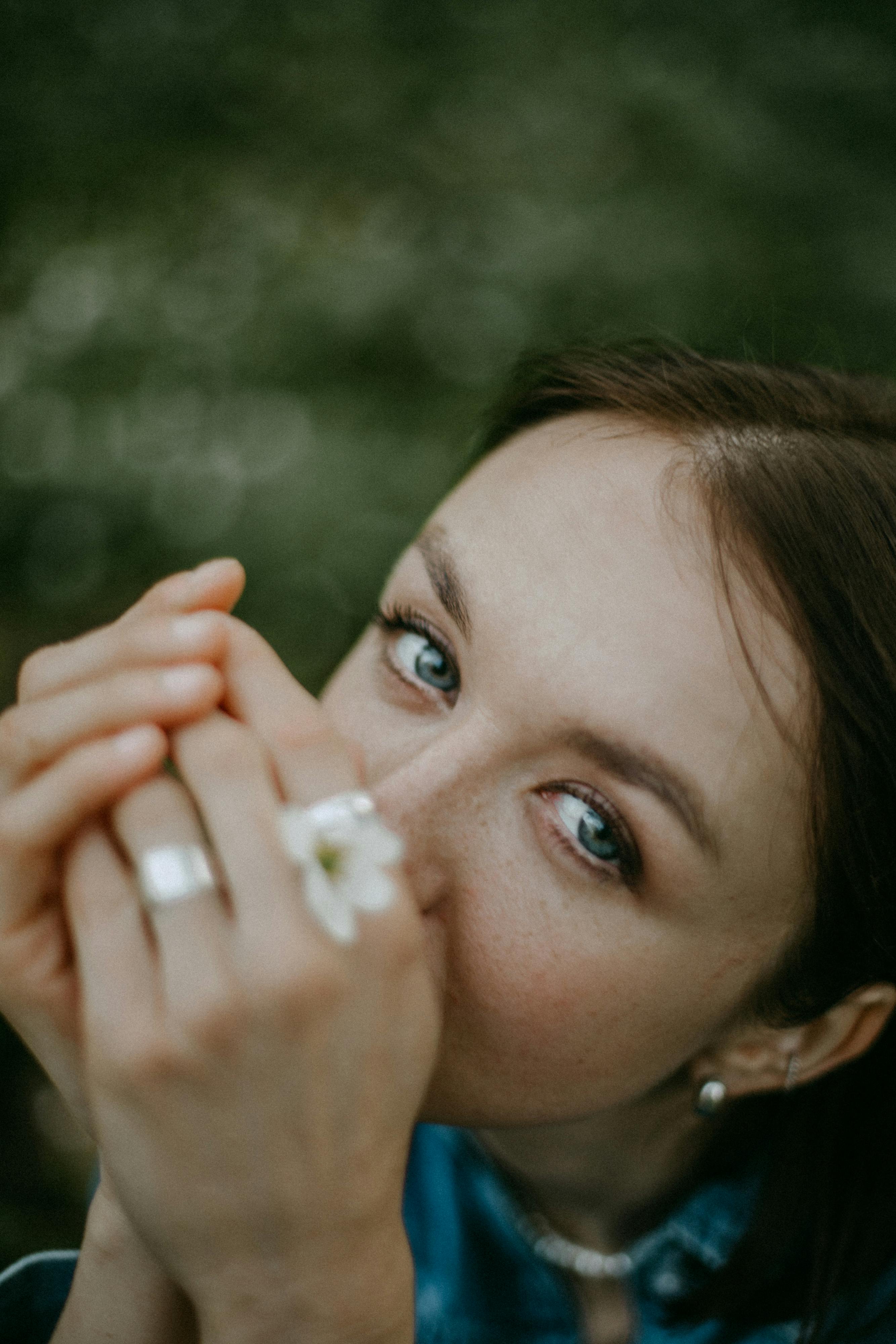 Intimate close-up portrait of a woman holding a small flower, capturing her delicate expression.