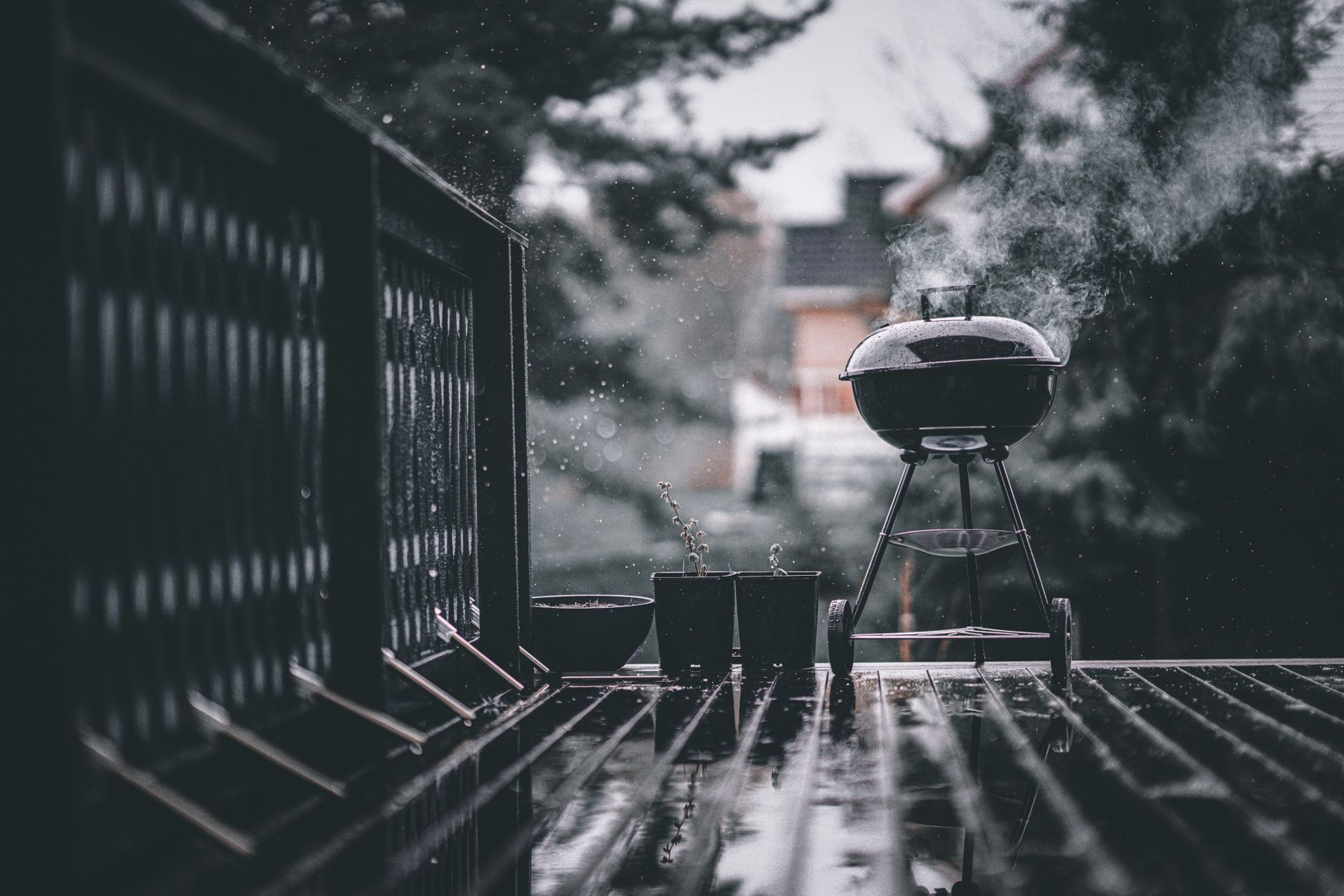 Smoke rolling off a kettle barbecue on a cold patio during a long cook