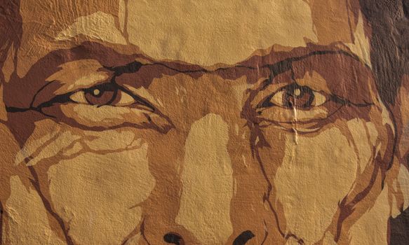 A detailed close-up of a street art mural capturing an expressive face with textured features.
