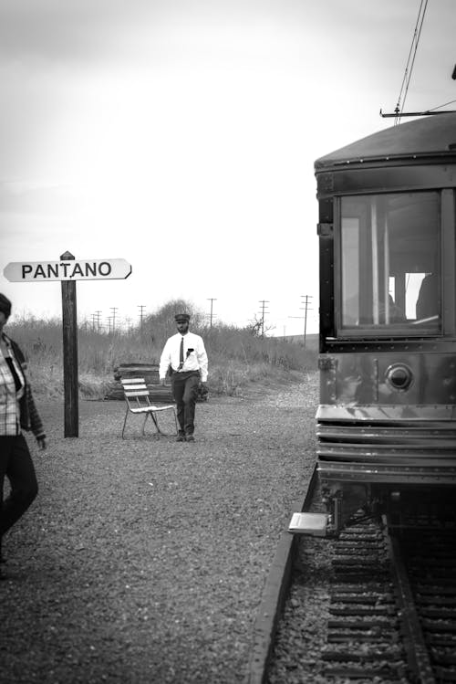 기차 근처를 걷는 남자의 회색조 사진