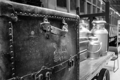 бесплатная Фотография дорожного чемодана с бидонами на прицепе в оттенках серого Стоковое фото