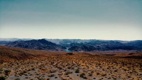 Brown Sand Near Mountain Under Cloudy Sky