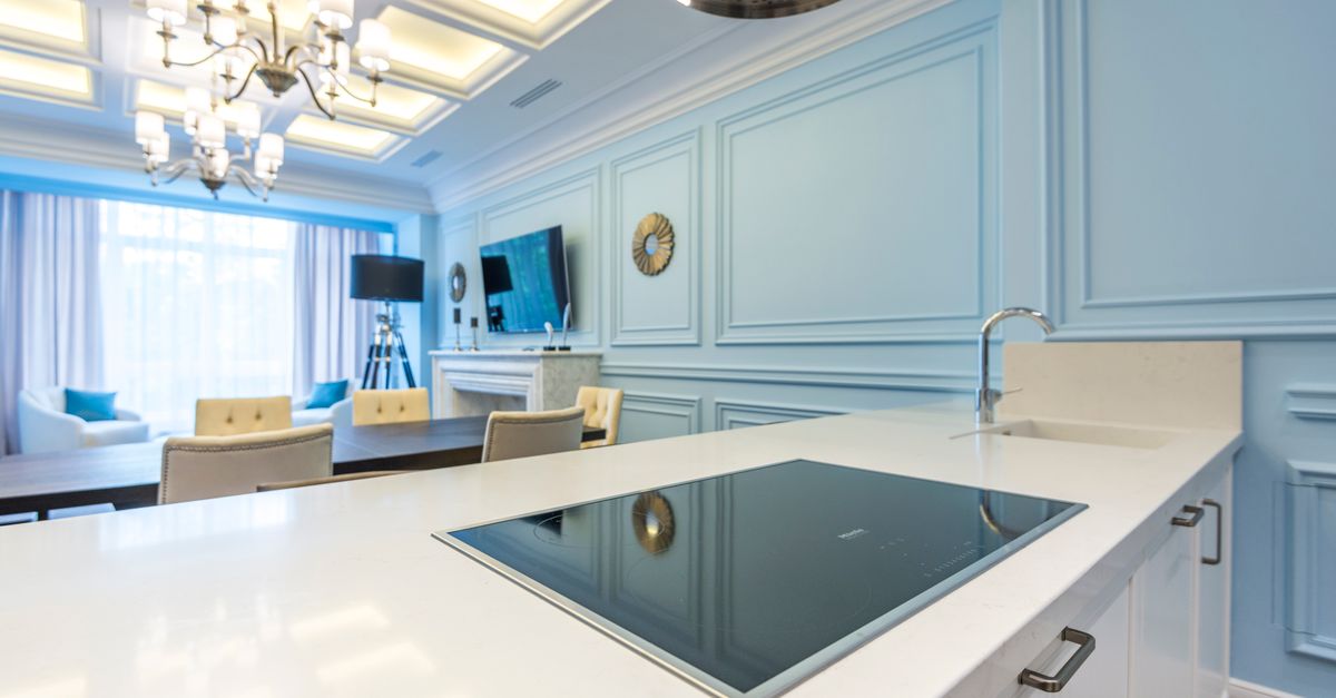 Stylish modern kitchen interior with elegant blue accents, including a countertop and chandelier lighting.
