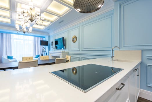 Stylish modern kitchen interior with elegant blue accents, including a countertop and chandelier lighting.
