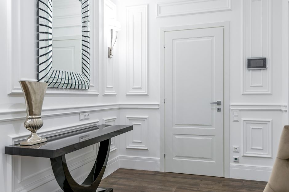 Luxurious white interior with modern decor, featuring a stylish mirror and elegant door.