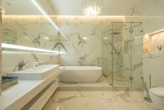 Elegant and modern marble bathroom with freestanding tub and glass shower.