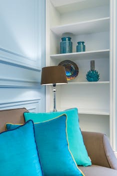 A stylish living room corner with vibrant throw pillows and elegant decor on the shelf.