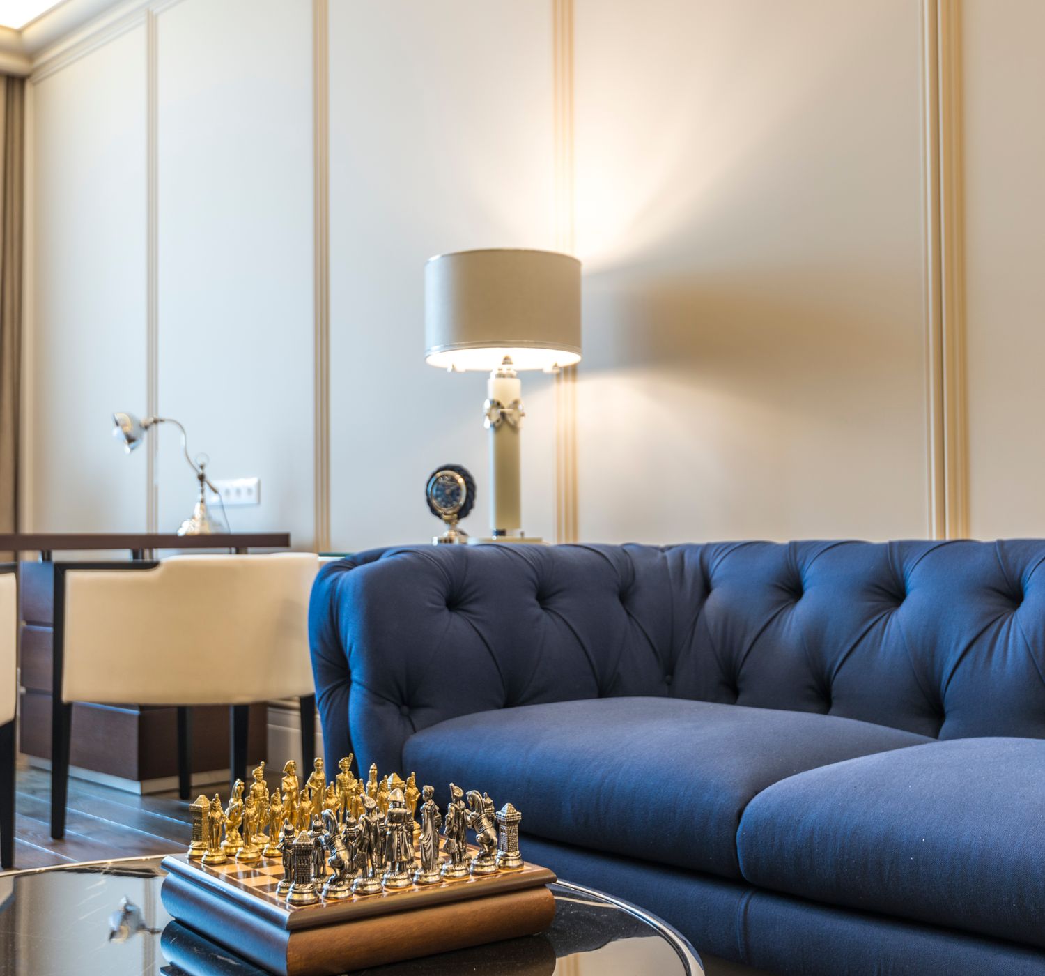 Stylish living room featuring a blue couch, chess set, lamps, and modern decor.
