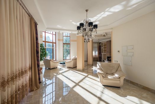 Luxurious living room featuring modern decor, large glass windows, and elegant chandelier.