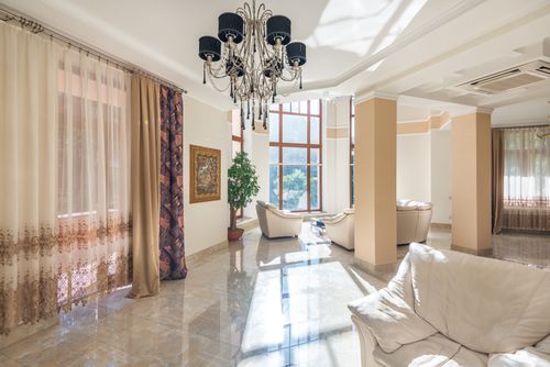 Free Spacious living room featuring elegant chandelier, large windows, and plush seating. Stock Photo