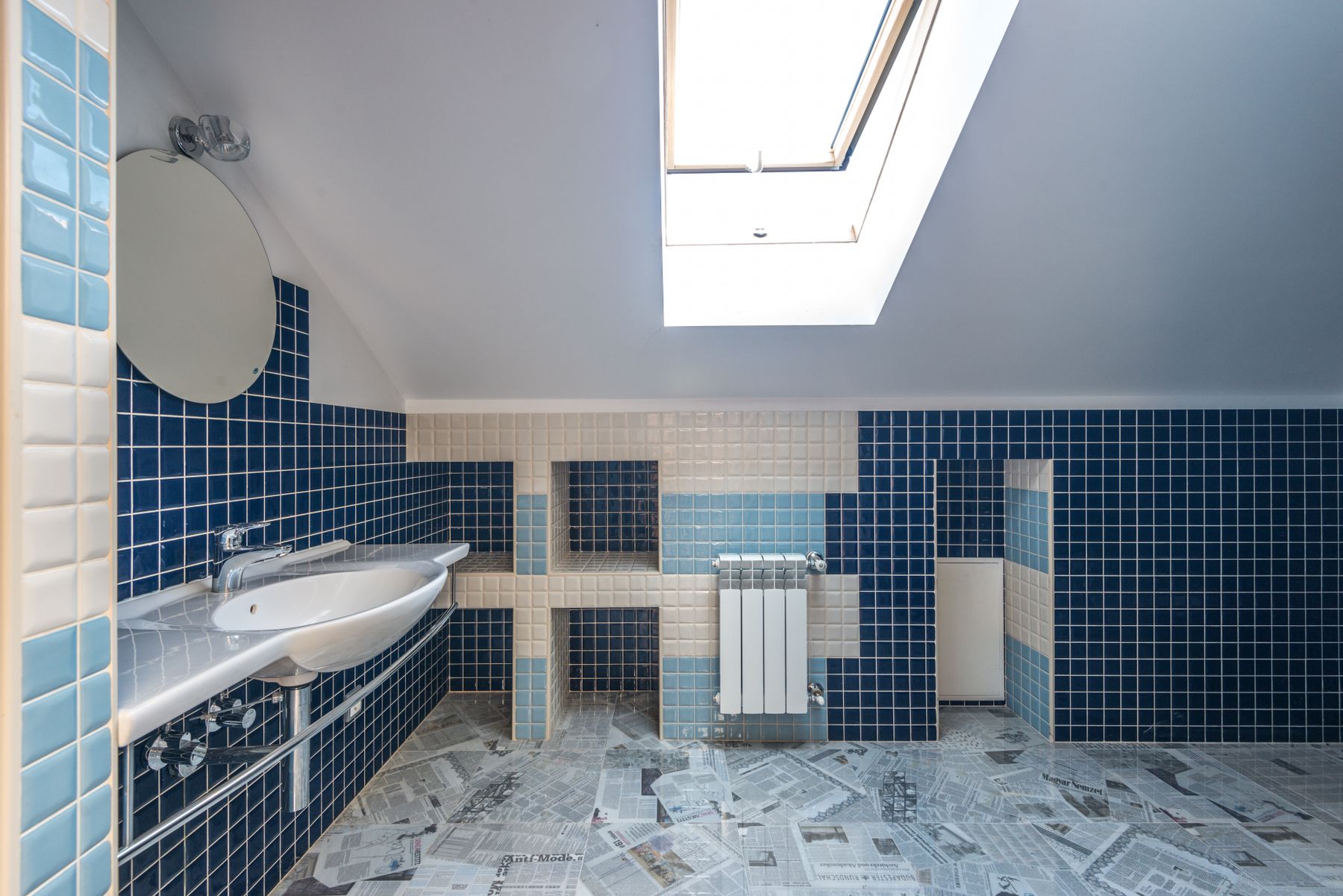 Blue and white bathroom illuminated by a skylight