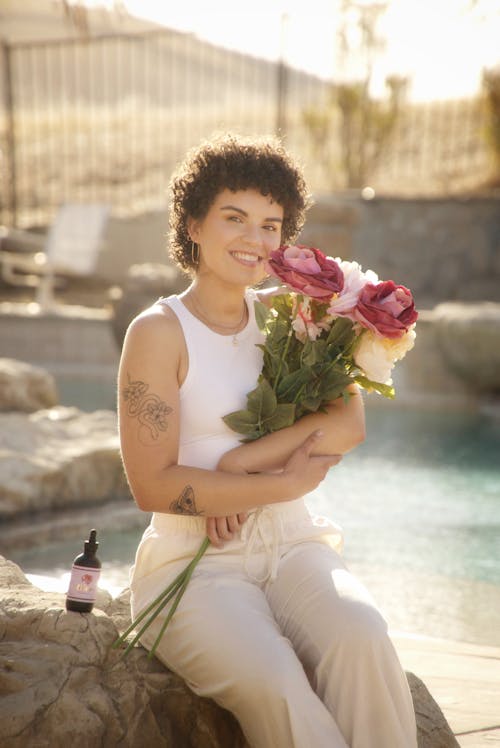 Free Woman in White Tank Top Holding Pink Rose Stock Photo