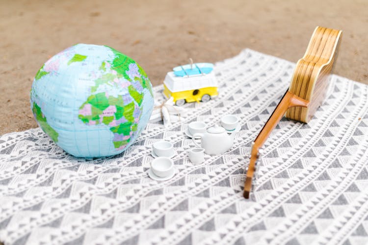 Toys, A Globe And A Ukulele On A Picnic Blanket