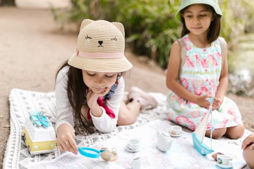 Free Kids Sitting on a Picnic Blanket while Playing Together Stock Photo