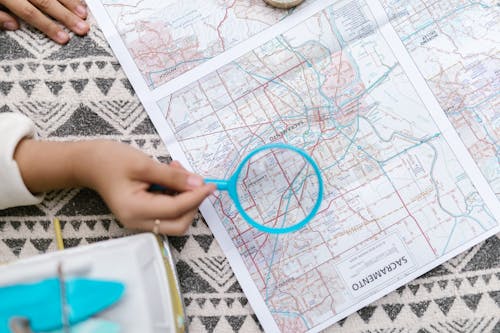 Person Holding Blue Magnifying Glass Over a Map