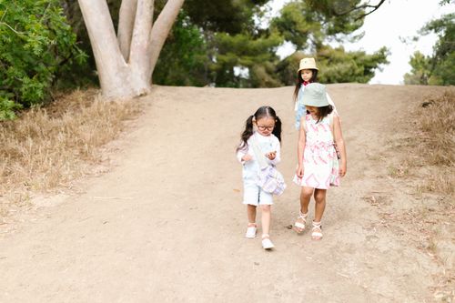 Free Three children walking outdoors on a dirt trail surrounded by trees, enjoying leisure time together. Stock Photo