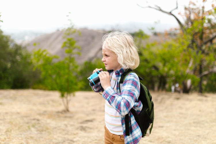 A Boy Holding A Binoculars