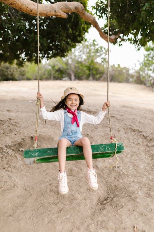A Girl in a Denim Jumper Sitting on a Swing