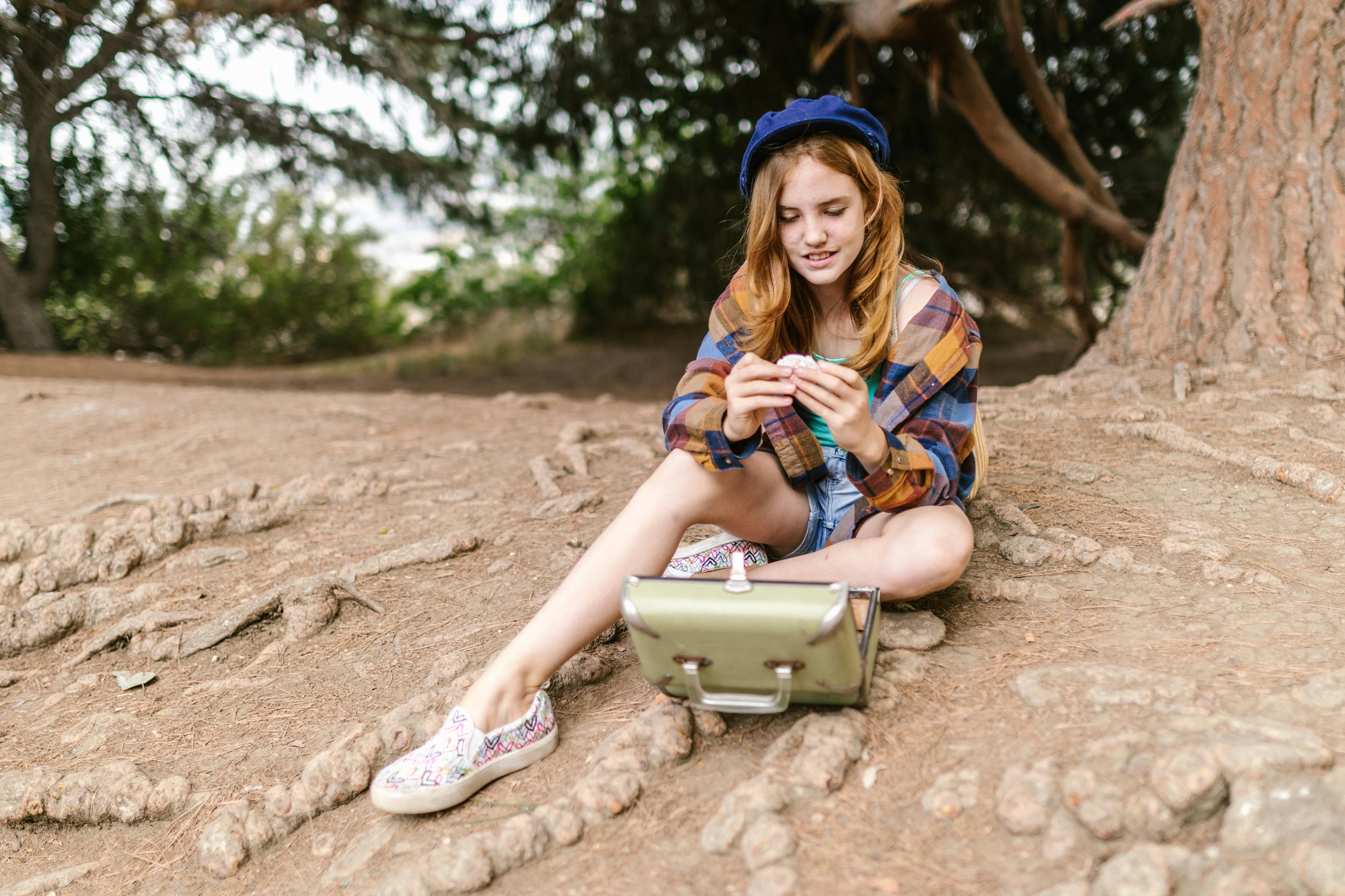 woman in blue and brown plaid shirt sitting on brown rock