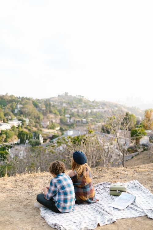 Free Children enjoying a scenic outdoor picnic on a hilltop with a city view, fostering friendship and adventure. Stock Photo