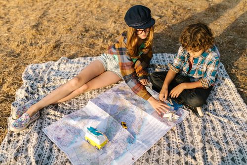 Free Two kids on a blanket exploring a map outdoors, dreaming of travel adventures. Stock Photo