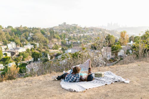 Free Two Teens Lying Down on Picnic Blanket while Looking at a Map Stock Photo
