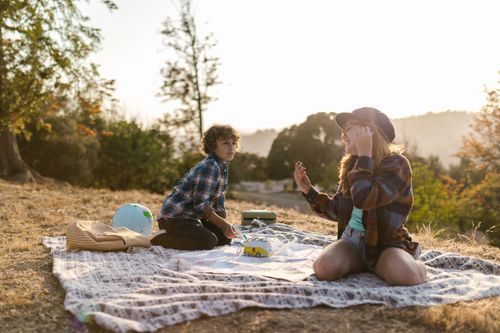 Free Two kids enjoying a playful picnic outdoors during summer, surrounded by nature. Stock Photo