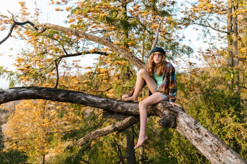 A Girl Sitting on a Tree Trunk in the Forest
