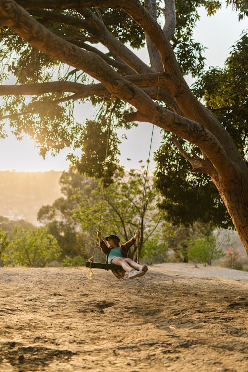 A Girl Riding a Swing Under a Tree