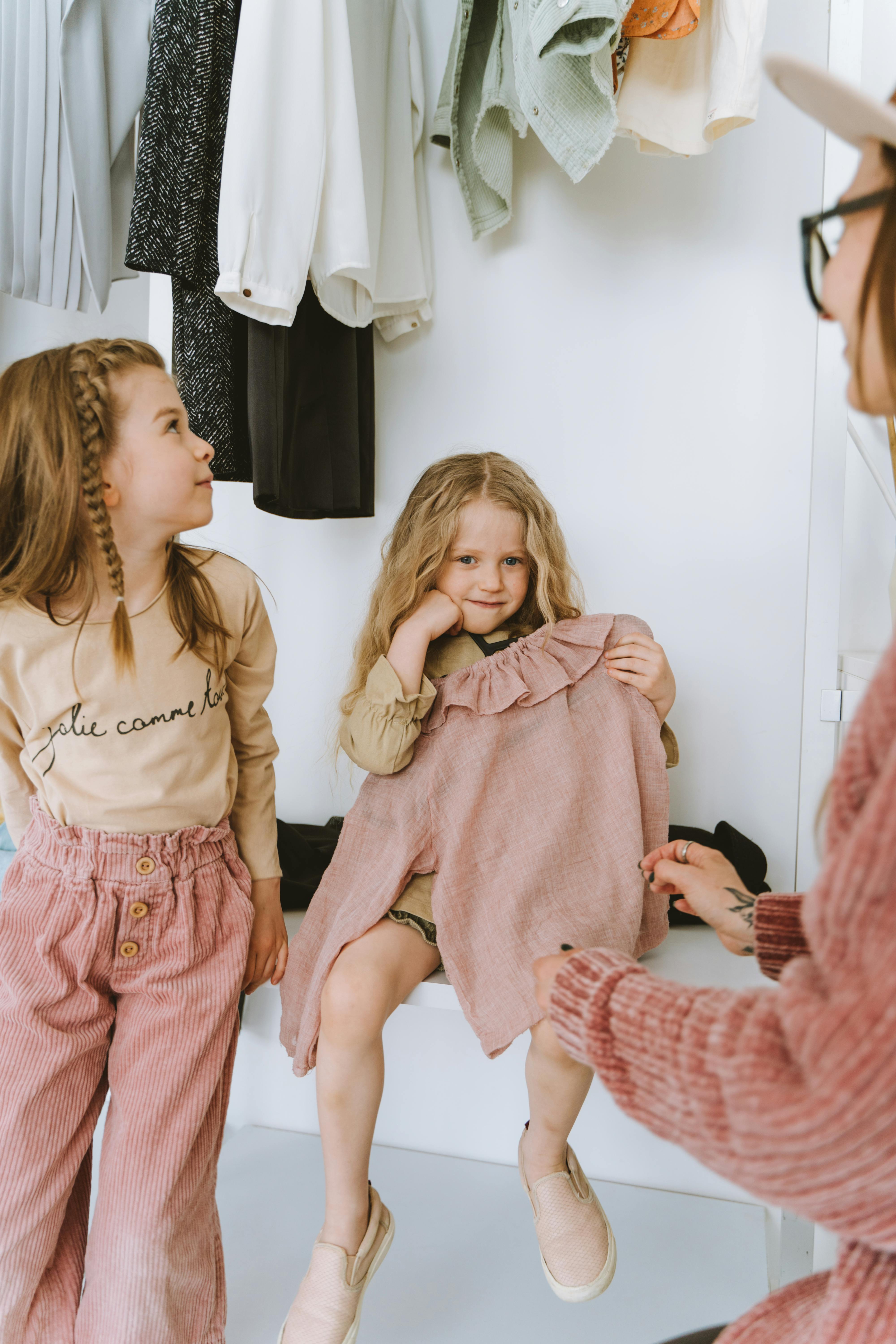 Two young girls having a fun dress-up session with their mother in the closet.