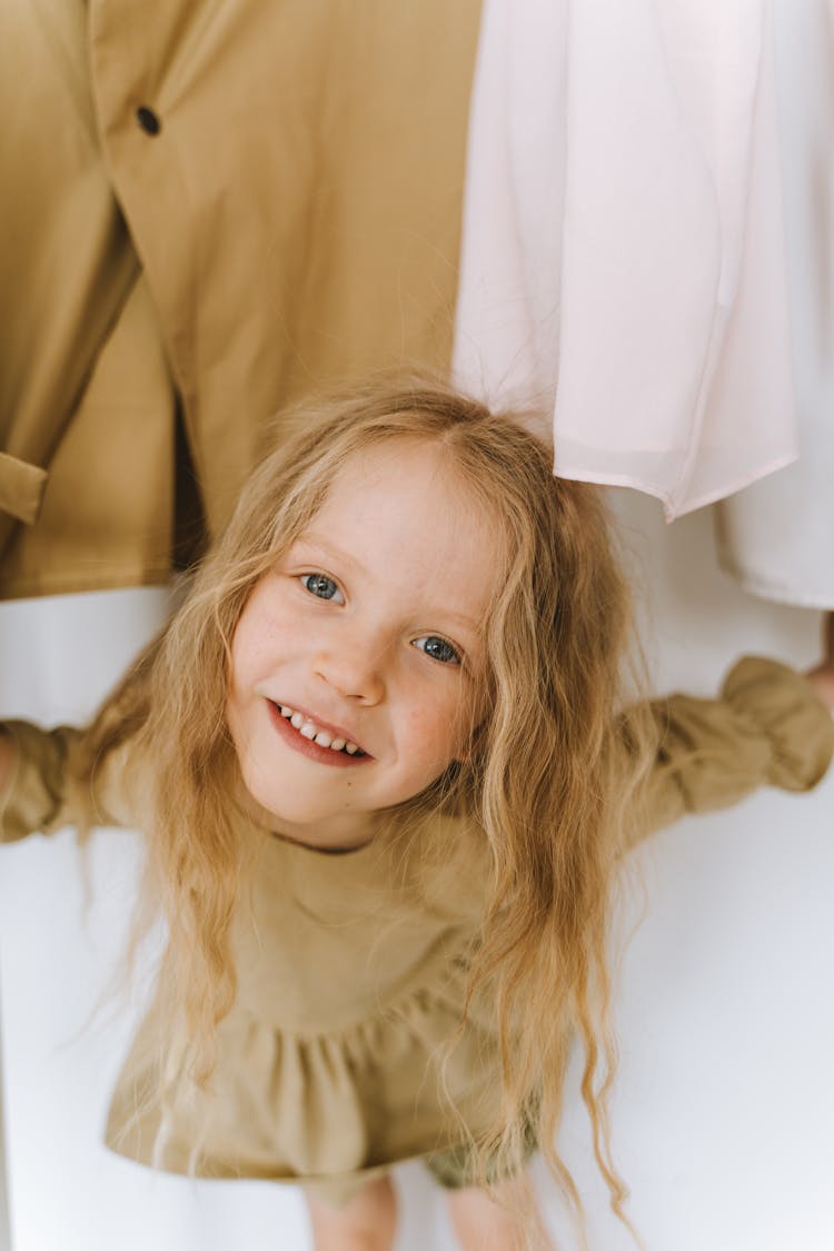 A Girl Standing Under Hanging Clothes While Smiling At The Camera