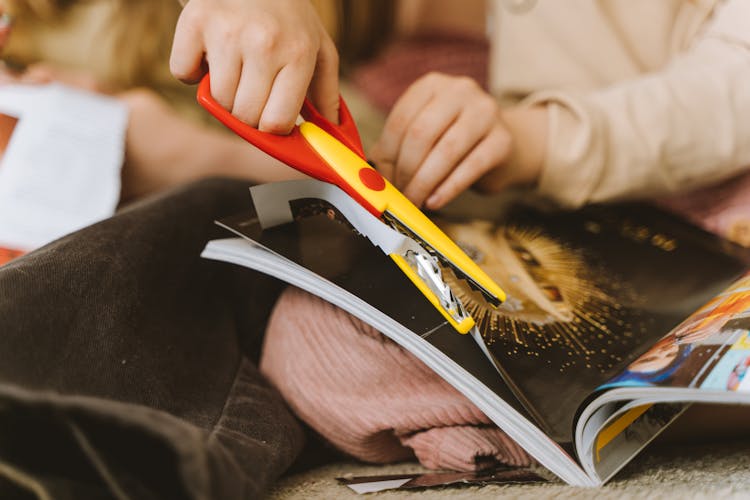 A Hand Cutting The Paper Using Scissors