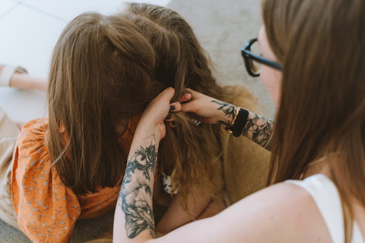 Woman Braiding A Child's Long Hair