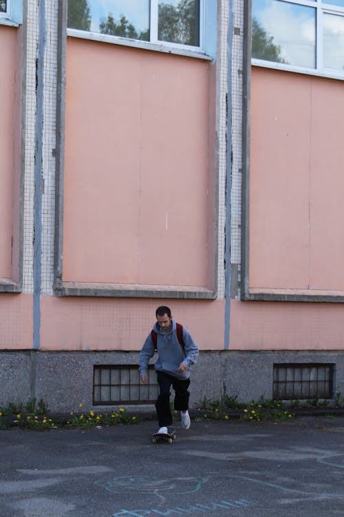 A Man in Gray Hoodie Riding a Skateboard