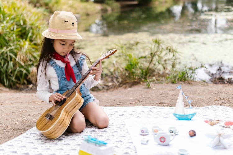 A Girl Playing The Ukulele During A Picnic