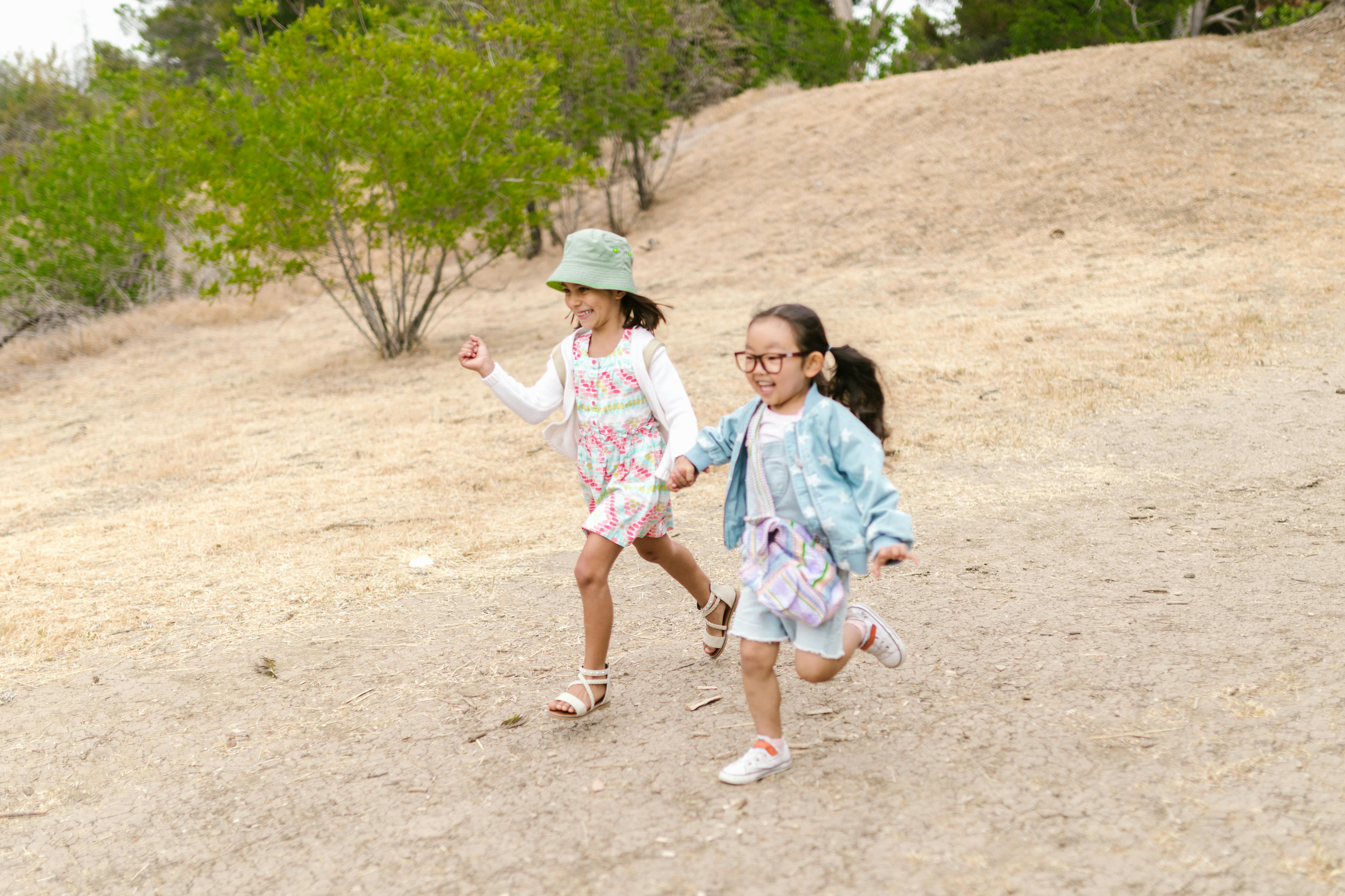 Two children running joyfully together on a sunny day, showcasing carefree fun and friendship.