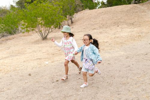 Free Two children running joyfully together on a sunny day, showcasing carefree fun and friendship. Stock Photo
