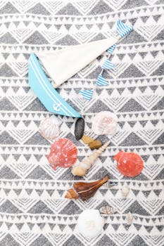 Nautical themed flat lay featuring seashells on a geometric patterned fabric.
