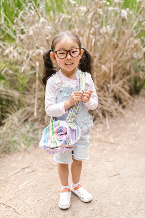Free Happy child with eyeglasses, wearing denim overalls, smiling outdoors in nature. Stock Photo