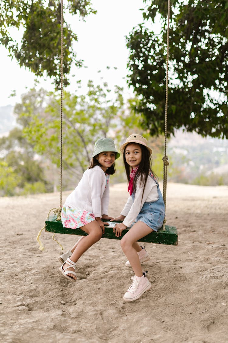 Two Girls Sitting On A Swing