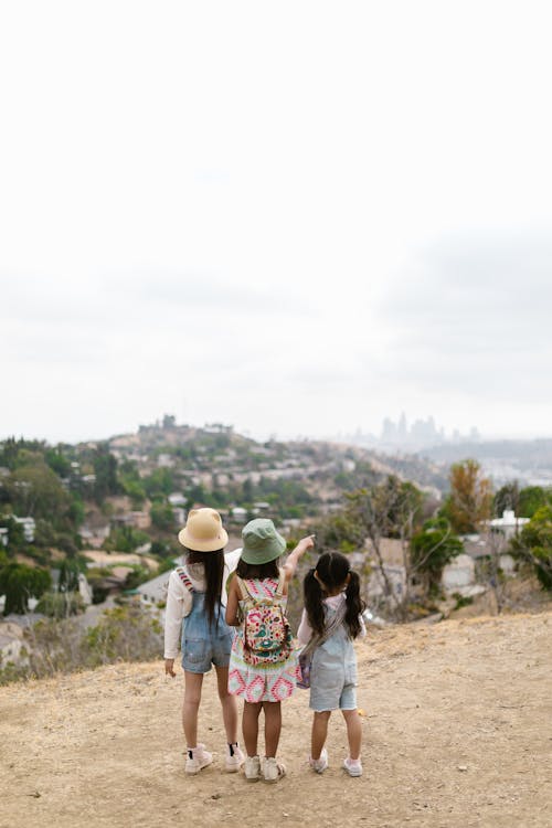 Back View of Three Girls Standing on the Road Looking at the View 