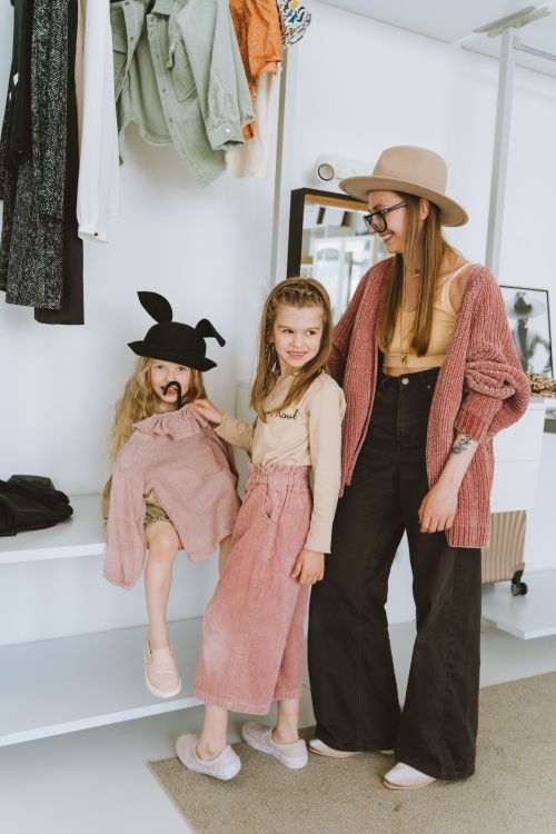 Free A stylish mother and daughters share a playful moment while trying on outfits in a modern room. Stock Photo