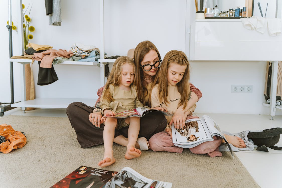 Woman and Two Girls Browsing on Magazines
