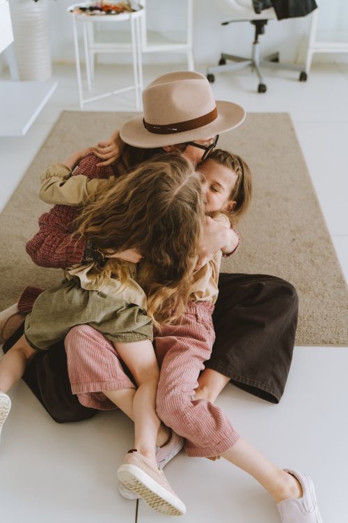 Free A loving mother embraces her daughters in a warm, joyful moment of family bonding at home. Stock Photo