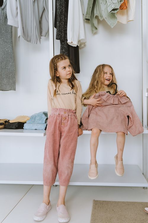 Free Two smiling sisters enjoying a cozy moment together in a wardrobe setting, radiating joy and warmth. Stock Photo