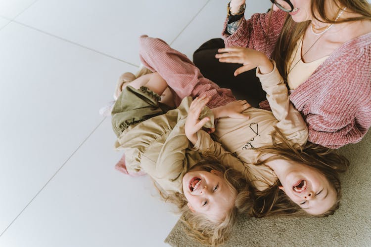 Photo Of Siblings Laughing Beside Their Mother