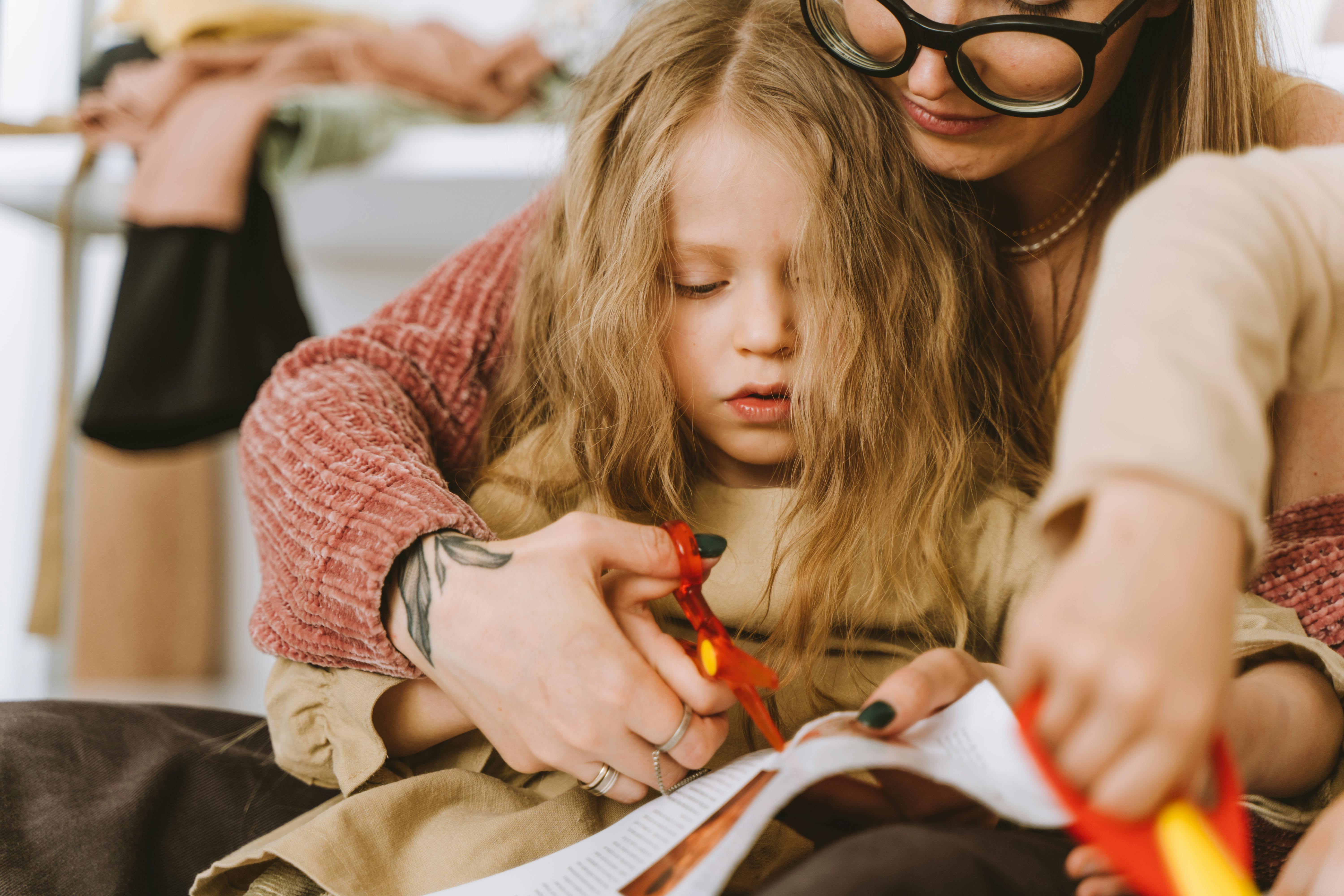 a mother helping her daughter cutting paper