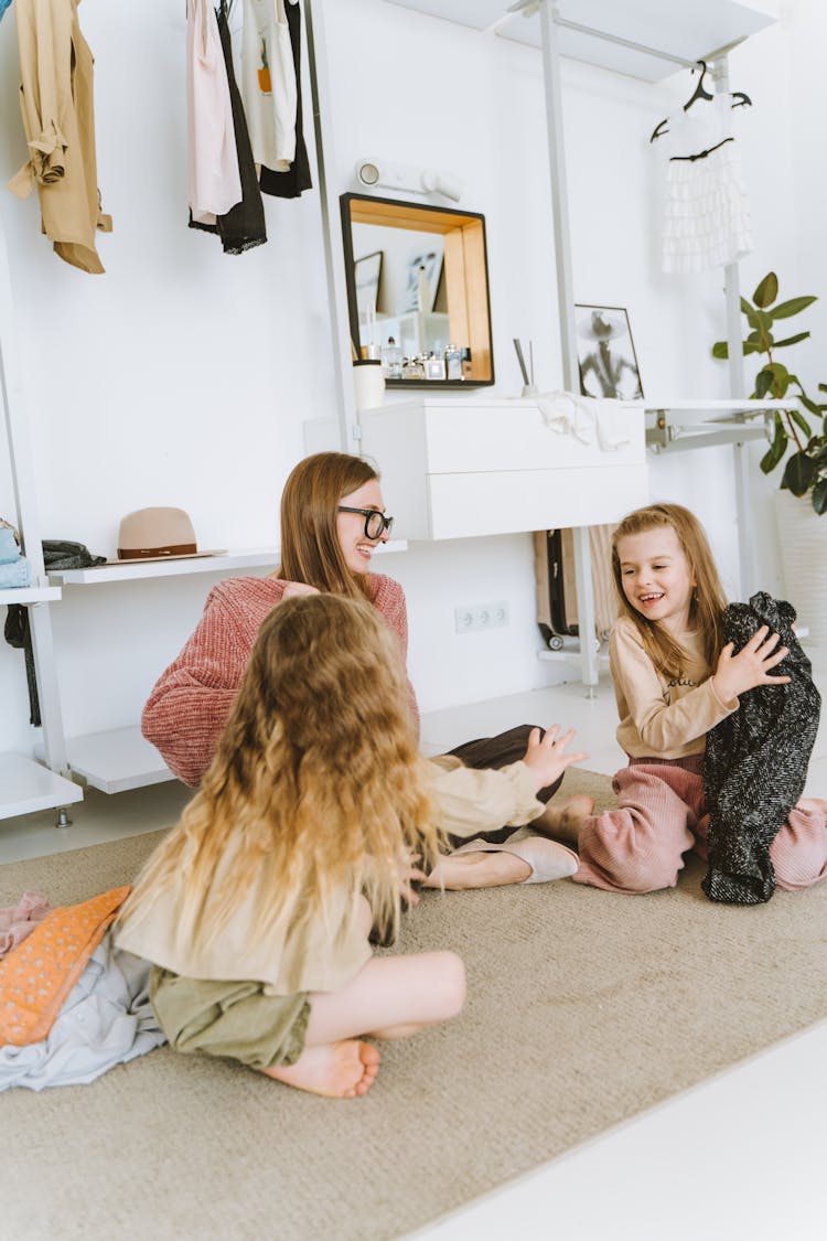 Mother And Kids Sitting On The Carpet While Laughing Together